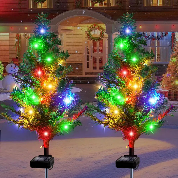 Four solar mini Christmas trees lit on lawn