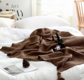 Knitted throw with pom-pom fringe on a sofa